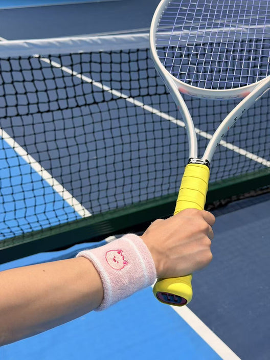 A pink Pupcourt cavoodle wristband on a player holding a racket at the net